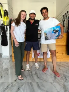 Newly certified SSI Open Water Divers with instructor Moudi Heikal holding certification manual at Deep South Divers Marsa Alam